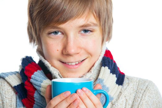 Portrait of young smiling cute frozen teenager in a scarf and with blue cup, isolated on white,