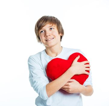 A cute young boy in love with a red plush heart in his hands. Focus on the heart.