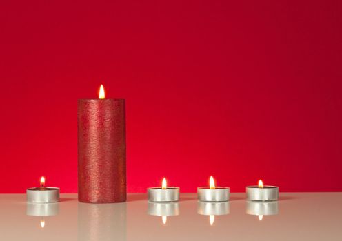 Five burning candles over red background