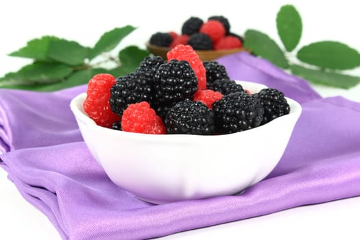 a white bowl with blackberries and raspberries