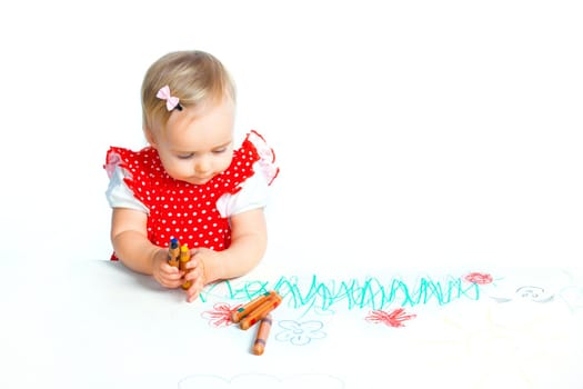 A little sweet girl draws with crayons in red, isolated on white