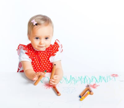 A little sweet girl draws with crayons in red, isolated on white