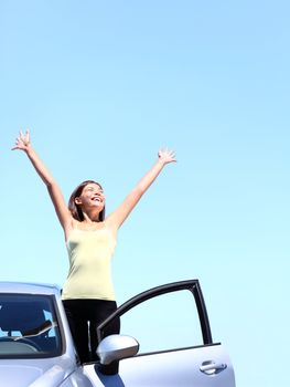 Car woman happy freedom concept. Cheering young woman with arms raised stepping out of new car under blue sky. Beautiful young multiracial Asian / Caucasian female model free.