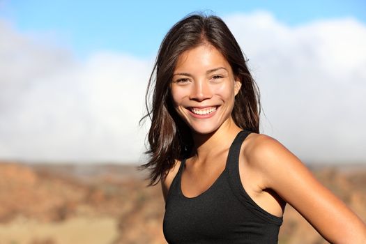sporty outdoor mixed race woman smiling happy after workout running outside in mountain landscape. Portrait of fresh healthy multiracial Asian / Caucasian fitness model.