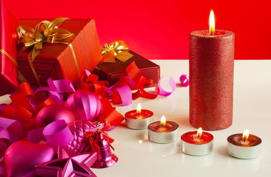 Christmas gifts and four candles over red background