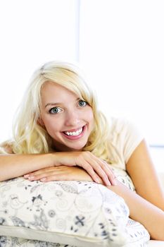 Portrait of smiling blonde woman relaxing on couch in living room at home