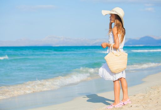 Adorable beautiful girl wearing elegant hat having fun on the tropical beach