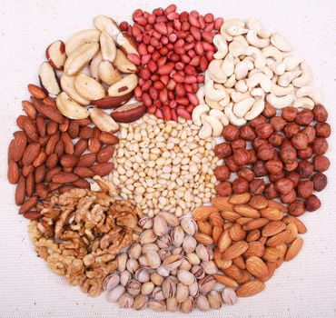 Assorted pine nuts, filbert, peanut, pistachios, walnut, almonds and  hazelnuts on natural sackcloth can use as background 

