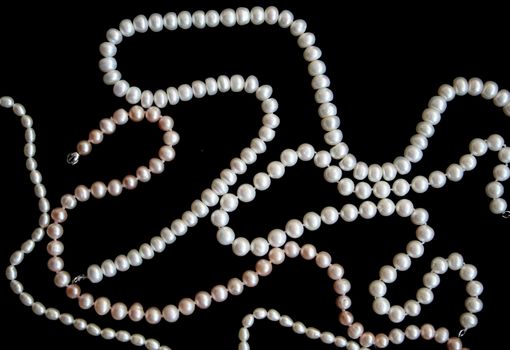 White pearls on the black silk as background 