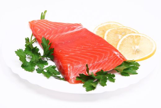 Salmon steak with lemon slices and parsley on white plate isolated on white background 