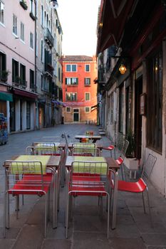 Urban scene. Few tables and chairs on narrow European street