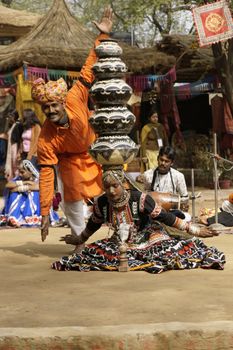 Female tribal dancer performing a dance involving balancing an increasing number of pots on her head at the annual Sarujkund Fair near Delhi, India.