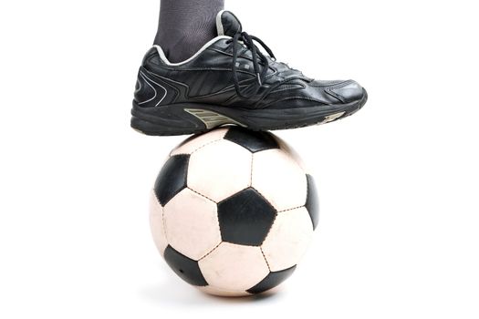 Foot on black white football or soccer sport ball