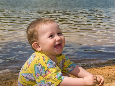 Little child smiling on water beach at summer