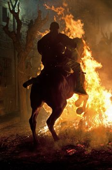 rider jumps the fire with his horse