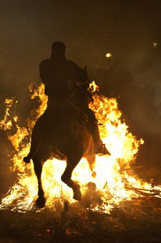 rider jumps the fire with his horse