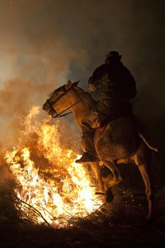 rider jumps the fire with his horse