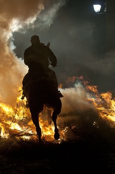 rider jumps the fire with his horse