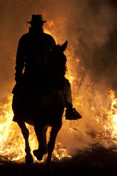 rider jumps the fire with his horse