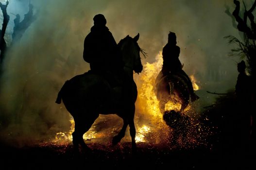 rider jumps the fire with his horse