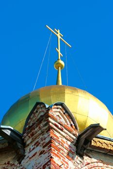 Church dome, topped with a gold cross on a dazzling blue sky. Rostov Veliky.