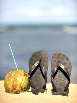 Thongs and coconut on the beach in Brazil.