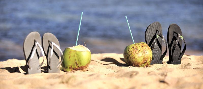 Thongs and coconut on the beach in Brazil.