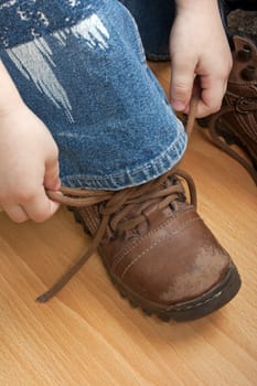 Little child boy hand tying foot sport shoe lace