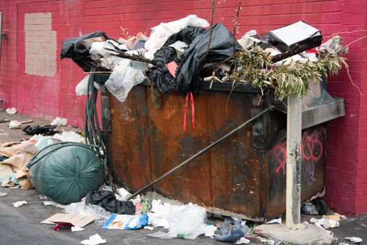 overfilled trash dumpster in ghetto neigborhood