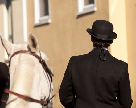 Man with kentucky or german top hat riding helmet on sunny day