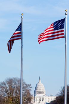 Capitol dome on a clear winter day with stars and stripes flag in foreground