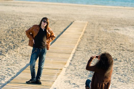 Woman taking photographs of a teenager on the beach