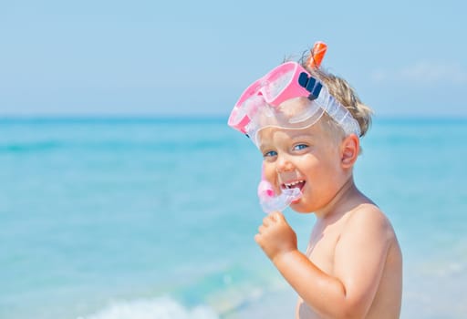 A cute little boy wearing a mask for diving background of the sea