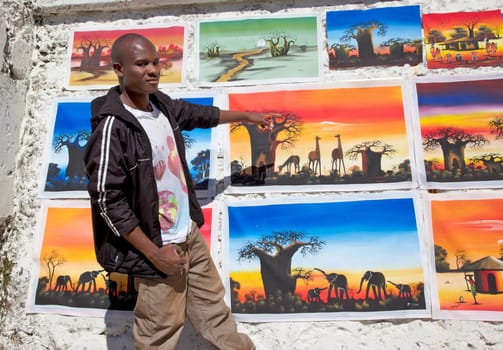 Cape Town, South Africa, December 4, 2011: South Africa is home to an estimated five-million illegal immigrants and the problem increases each day. Despite their qualifications, there is little work and much resentment for these illegal immigrants and some of them earn an income by creating African-themed art and curios. Here, a Malawian artist displays his colorful work at Kalk Bay Harbour, Cape Town.