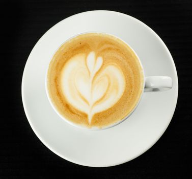 Cup of coffee with milk pattern on black table