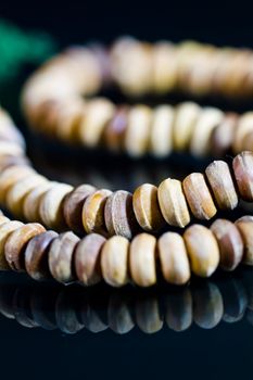 wooden rosary close up with green string on black mirror