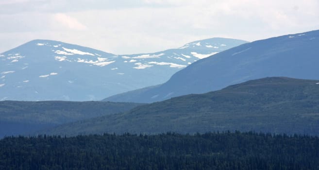 Four different shades of blue in distance mountains and forest.