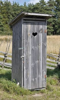 Small wooden outdoors toilet in summer.