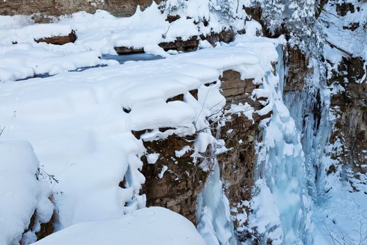 Image of a frozen waterfall in deep rock canyon. View from top