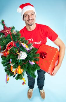 Happy smile young man in Santa hat with gifts and a Christmas tree