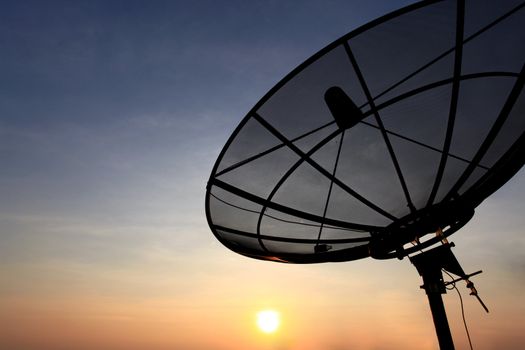 black antenna communication satellite dish over sunset sky in cityscape
