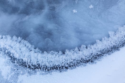 Image of frozen lake with ice edge covered with big icy snowflakes