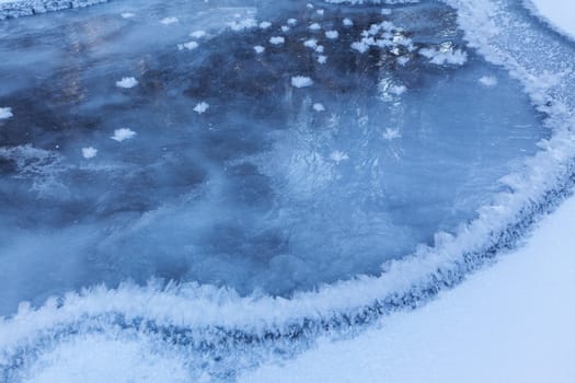 Image of frozen lake with ice edge covered with big icy snowflakes