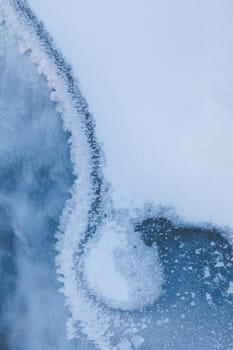 Image of frozen lake with ice edge covered with big icy snowflakes