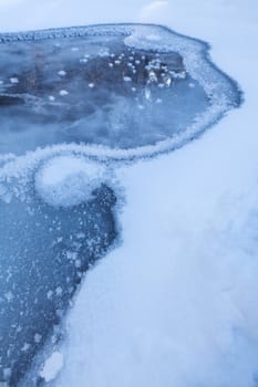 Image of frozen lake with ice edge covered with big icy snowflakes