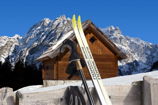 Nordic Skiing in the foreground and Wooden chalet in winter - Alps Italy