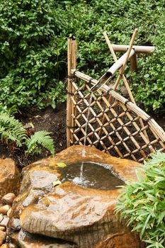 Bamboo fence and pipe, flows water in wood