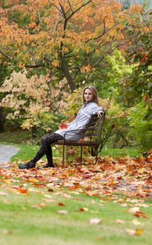 Girl on small bench in autumn park