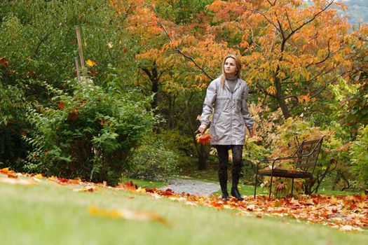 Beautiful girl goes on lane autumn park