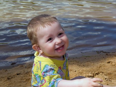 Little child smiling on water beach at summer